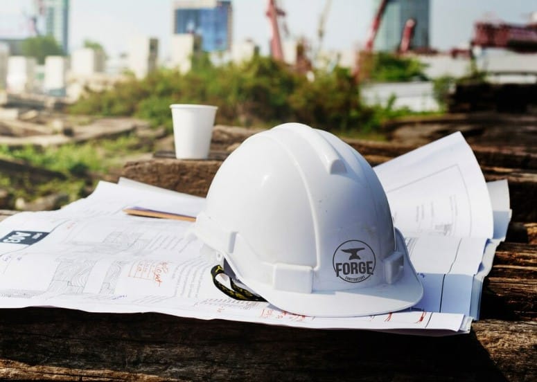 hard hat and blueprint with construction site in background